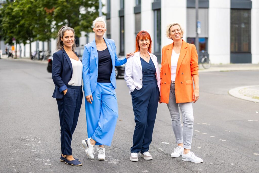 Das Mind-In Team steht auf einer Straße und lächelt