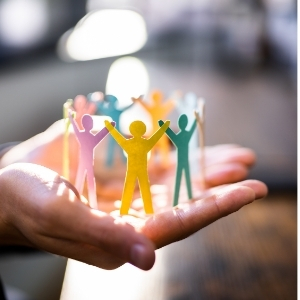 Hand hält bunte Papierfiguren als Symbol für Menschenkenntnis und Zusammenarbeit